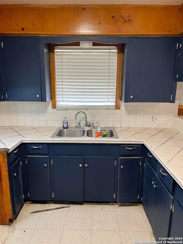 kitchen featuring sink, backsplash, tile countertops, and blue cabinets