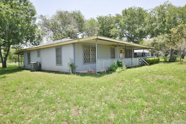 rear view of house featuring central AC and a lawn