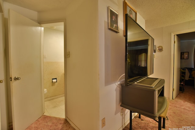 hall with light tile flooring and a textured ceiling