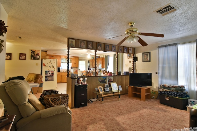 living room with light colored carpet, ceiling fan, and a textured ceiling