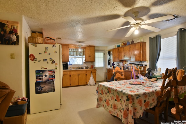 kitchen with white refrigerator, kitchen peninsula, ceiling fan, light tile floors, and a textured ceiling