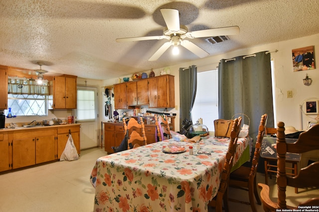 tiled dining space with sink, ceiling fan, and a textured ceiling