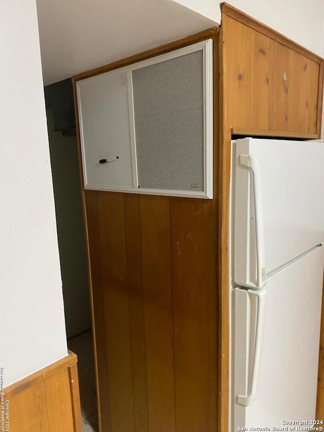 kitchen featuring white refrigerator and wooden walls