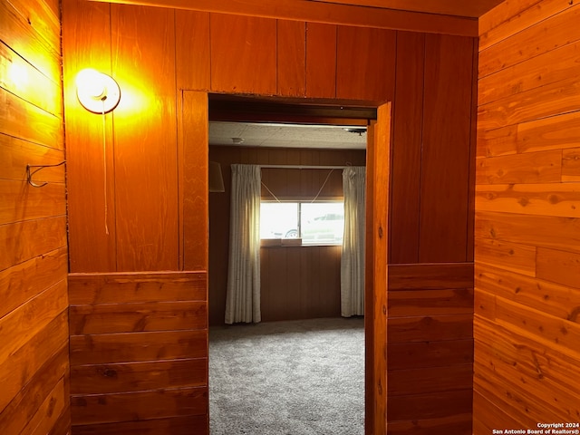 hall with carpet flooring and wood walls