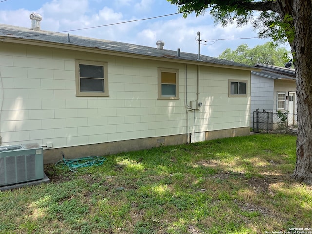 view of side of property featuring cooling unit and a yard