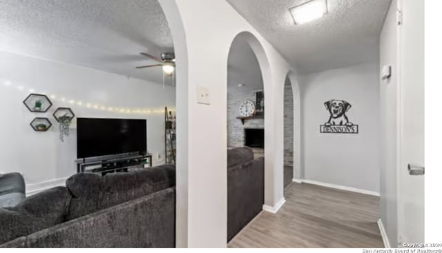 living room featuring hardwood / wood-style flooring, ceiling fan, and a textured ceiling