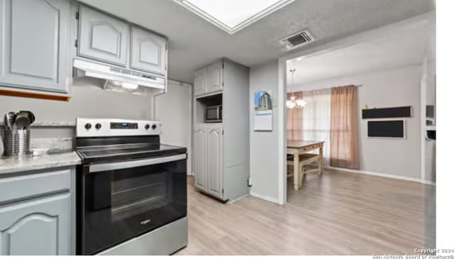 kitchen featuring an inviting chandelier, light hardwood / wood-style floors, fume extractor, gray cabinets, and appliances with stainless steel finishes