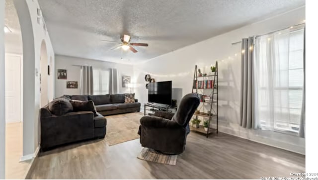 living room featuring a textured ceiling, wood-type flooring, and ceiling fan