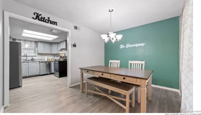 dining area featuring light wood-type flooring and a chandelier