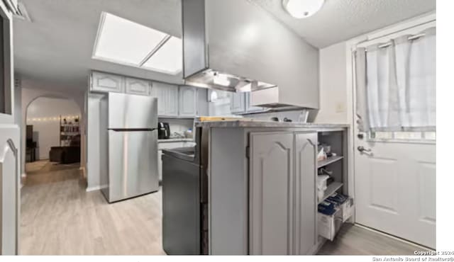 kitchen with stainless steel refrigerator, gray cabinetry, and light wood-type flooring