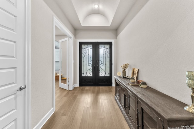 entrance foyer featuring a tray ceiling, light hardwood / wood-style floors, and french doors