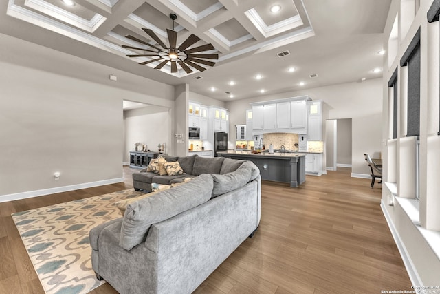 living room with beamed ceiling, ceiling fan, coffered ceiling, and light hardwood / wood-style flooring