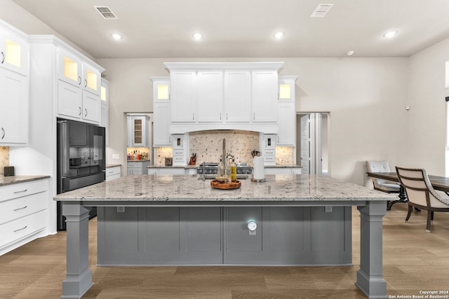 kitchen featuring a spacious island, hardwood / wood-style floors, backsplash, and white cabinets