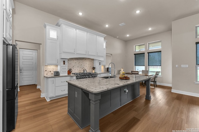 kitchen featuring sink, white cabinetry, hardwood / wood-style flooring, and a kitchen island with sink