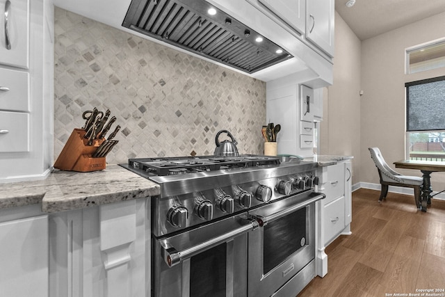 kitchen featuring premium range hood, white cabinets, hardwood / wood-style flooring, and high end stove