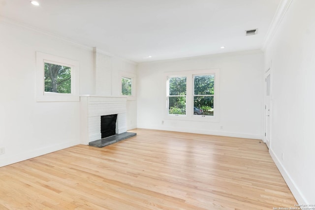 unfurnished living room with crown molding, light hardwood / wood-style flooring, and a brick fireplace