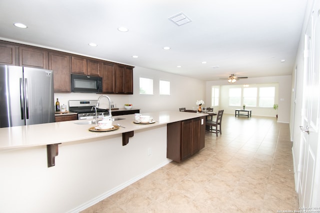 kitchen with stainless steel appliances, light tile floors, a wealth of natural light, and a breakfast bar