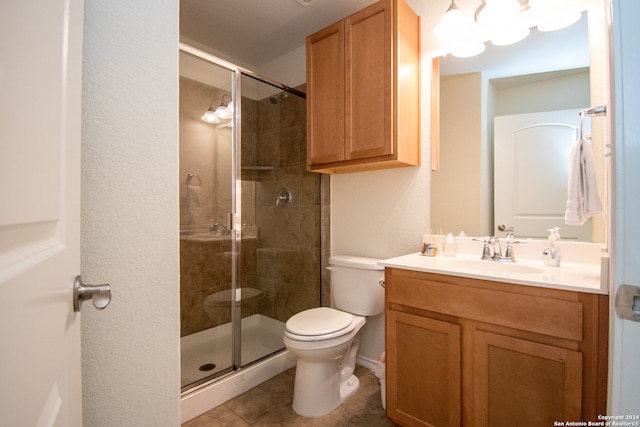 bathroom featuring tile flooring, a shower with shower door, toilet, and vanity