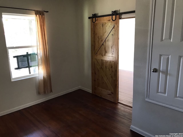 spare room featuring dark hardwood / wood-style flooring and a barn door