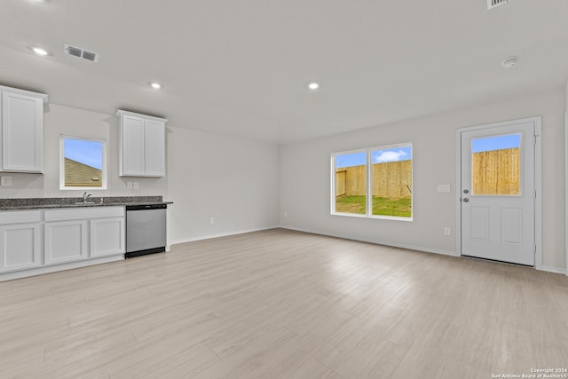 unfurnished living room featuring sink, a wealth of natural light, and light hardwood / wood-style flooring