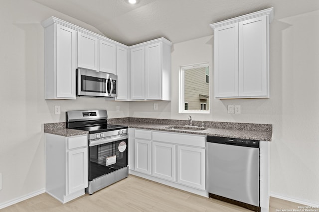 kitchen with white cabinets, stainless steel appliances, and light hardwood / wood-style flooring