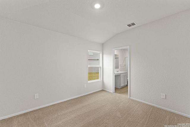 unfurnished room with light colored carpet and lofted ceiling