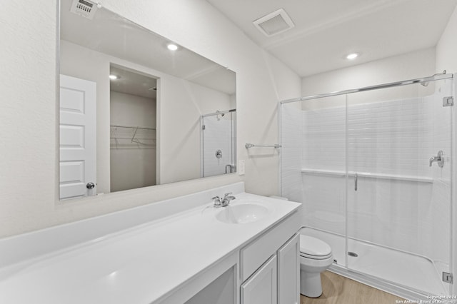 bathroom with walk in shower, toilet, vanity, and hardwood / wood-style flooring