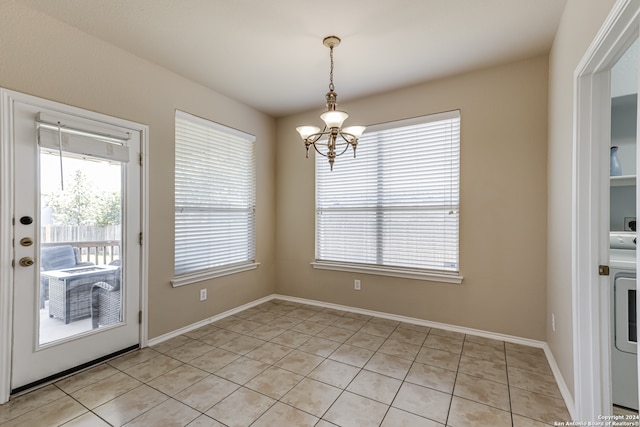 unfurnished dining area with washer / clothes dryer, light tile flooring, and a chandelier