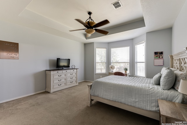 carpeted bedroom with ceiling fan and a raised ceiling