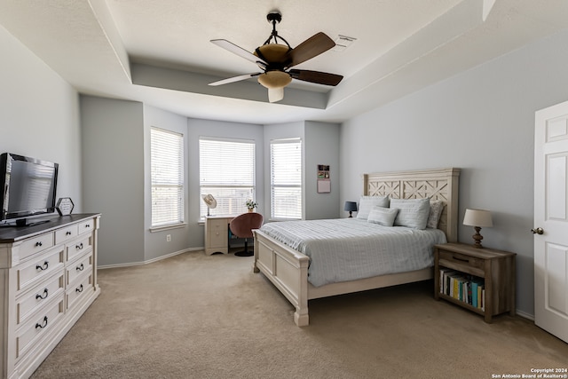 carpeted bedroom featuring ceiling fan and a tray ceiling