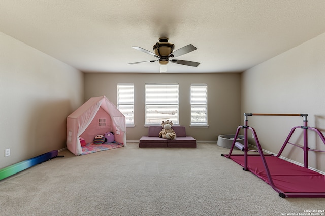 recreation room featuring ceiling fan, carpet floors, and a textured ceiling