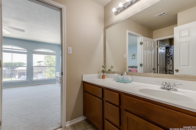 bathroom with tile floors, vanity, ceiling fan, and a textured ceiling