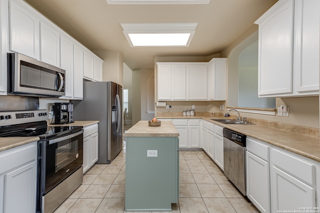 kitchen with stainless steel appliances, sink, a center island, and light tile floors