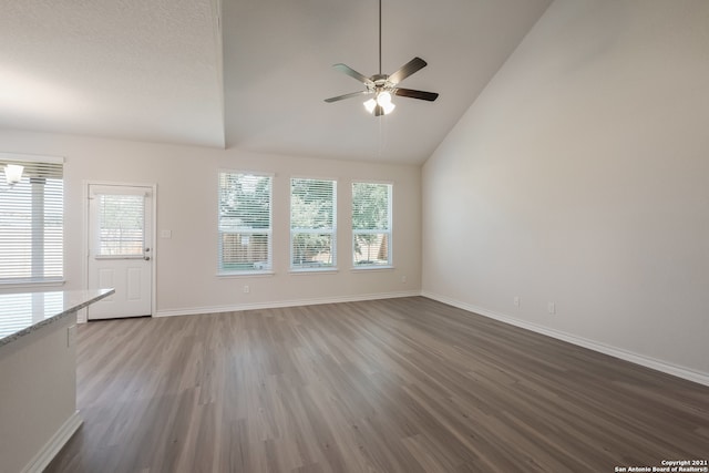 unfurnished living room with a ceiling fan, high vaulted ceiling, baseboards, and wood finished floors