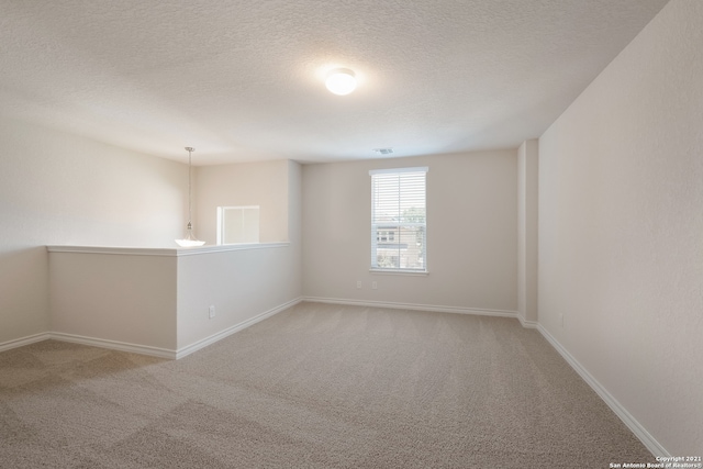 carpeted spare room featuring a textured ceiling, visible vents, and baseboards