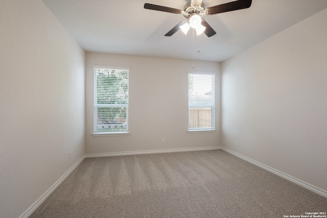 carpeted spare room with a ceiling fan and baseboards