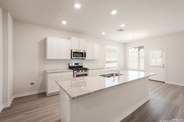 kitchen featuring light wood finished floors, visible vents, decorative backsplash, appliances with stainless steel finishes, and a sink