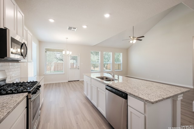 kitchen featuring stainless steel appliances, visible vents, light wood-style flooring, decorative backsplash, and a sink