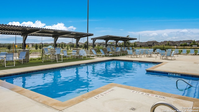 pool with fence, a pergola, and a patio