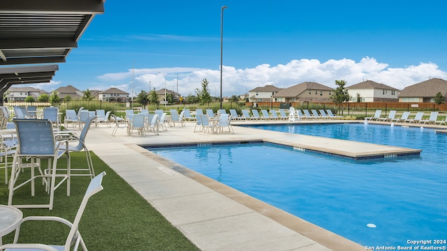 community pool with a residential view, fence, and a patio