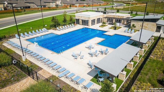 community pool featuring a patio area, fence, and a residential view