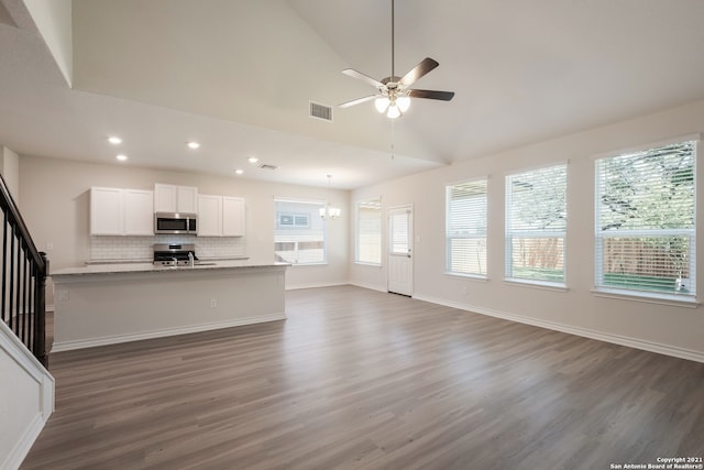 unfurnished living room featuring visible vents, dark wood finished floors, baseboards, stairway, and ceiling fan with notable chandelier