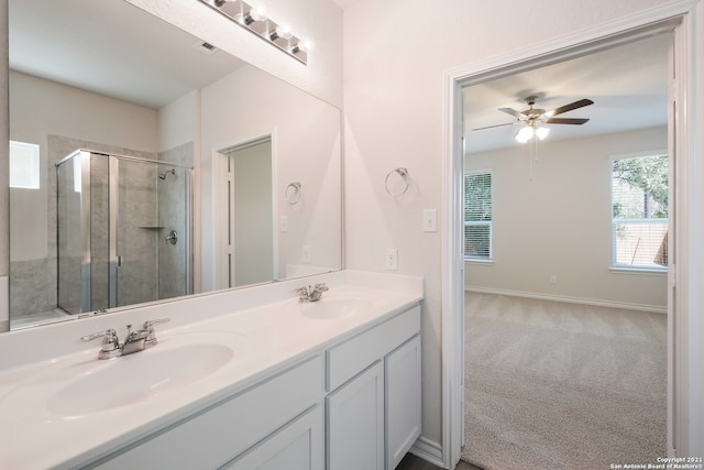 full bath with double vanity, a shower stall, a ceiling fan, and a sink