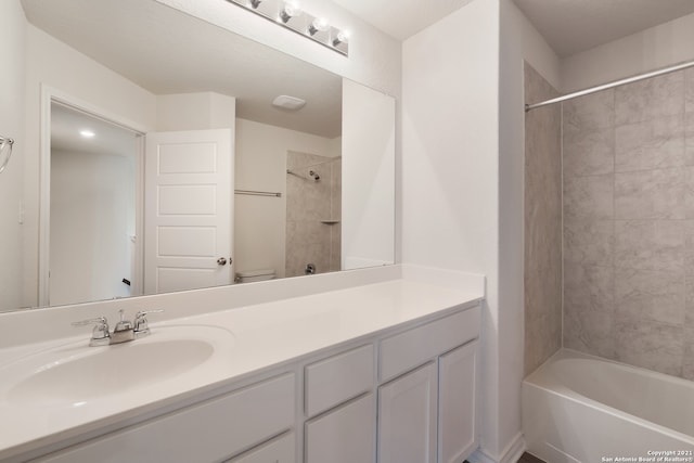 full bathroom with tiled shower / bath, vanity, and toilet