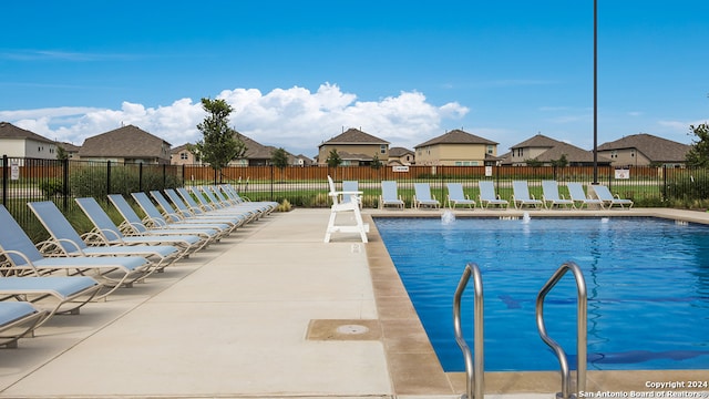 community pool featuring a residential view, a patio area, and fence