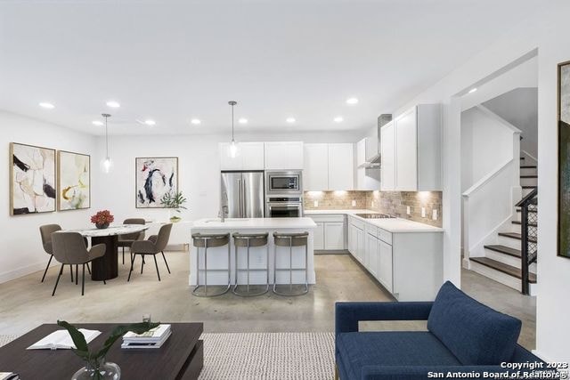 kitchen featuring a kitchen island, hanging light fixtures, tasteful backsplash, white cabinetry, and appliances with stainless steel finishes