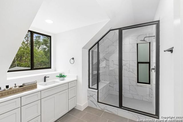 bathroom with lofted ceiling, vanity, tile floors, and a shower with door