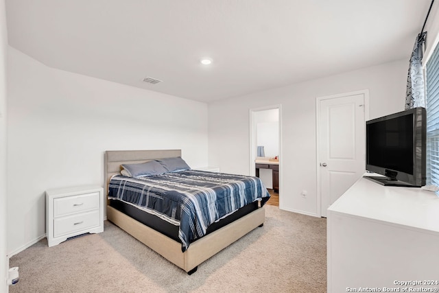 bedroom with light carpet and ensuite bathroom