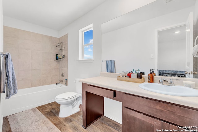 full bathroom featuring tiled shower / bath, hardwood / wood-style flooring, toilet, and vanity