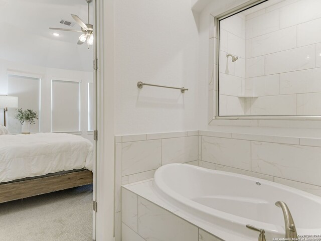 bathroom with tiled bath and ceiling fan